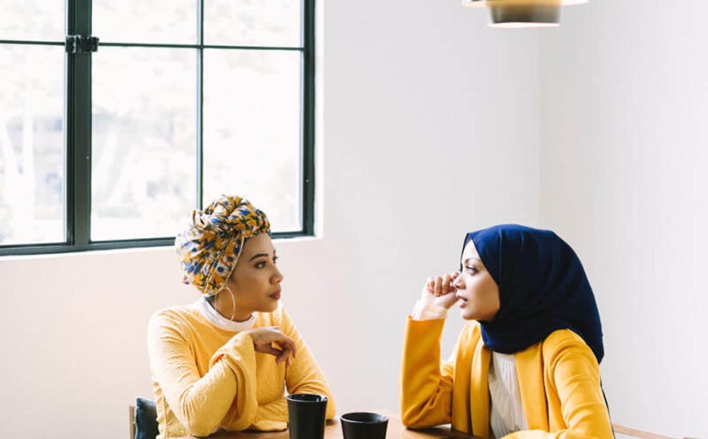 Two people sit in a table talking both wearing yellow