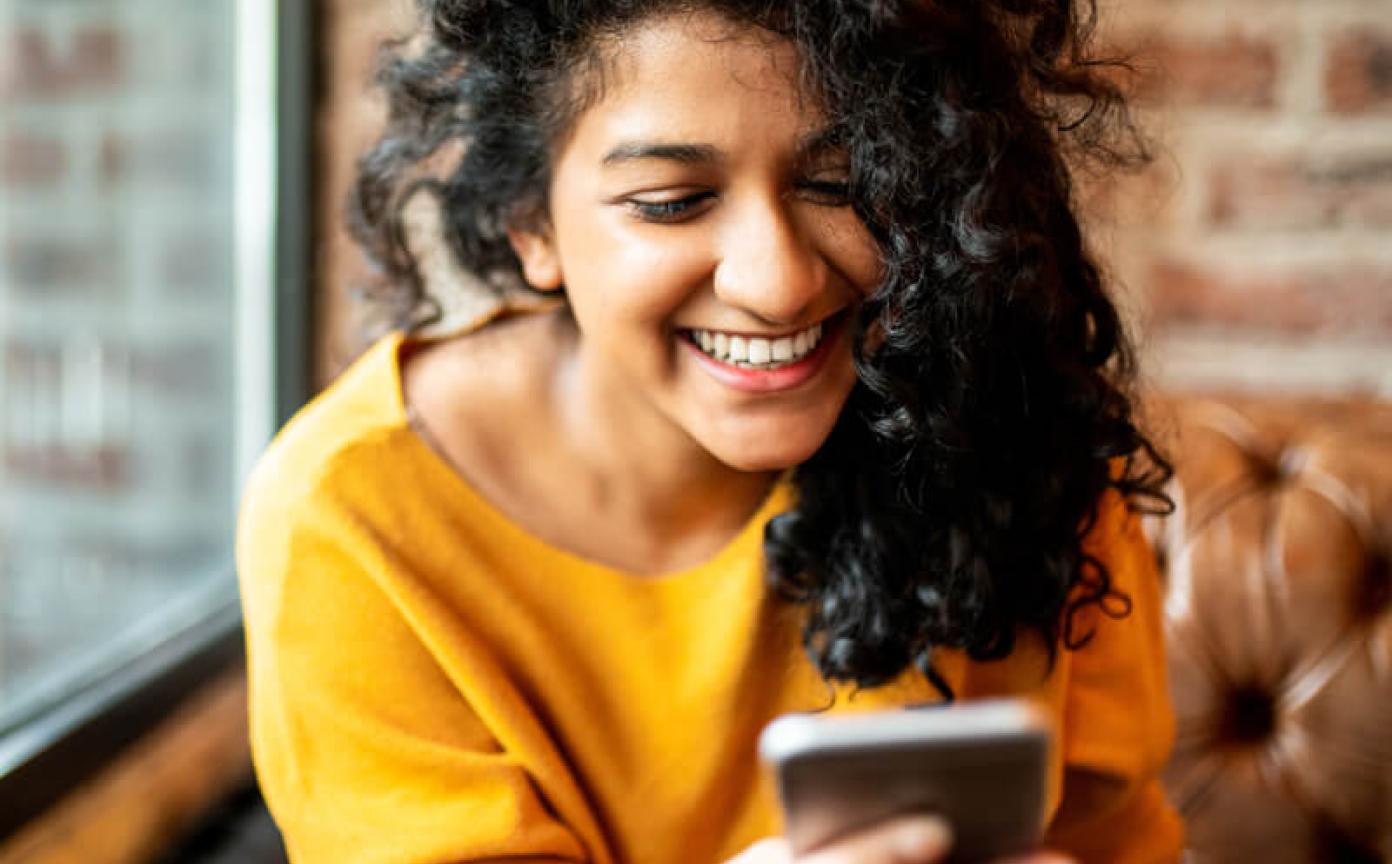 Person smiling with a cellphone in their hands