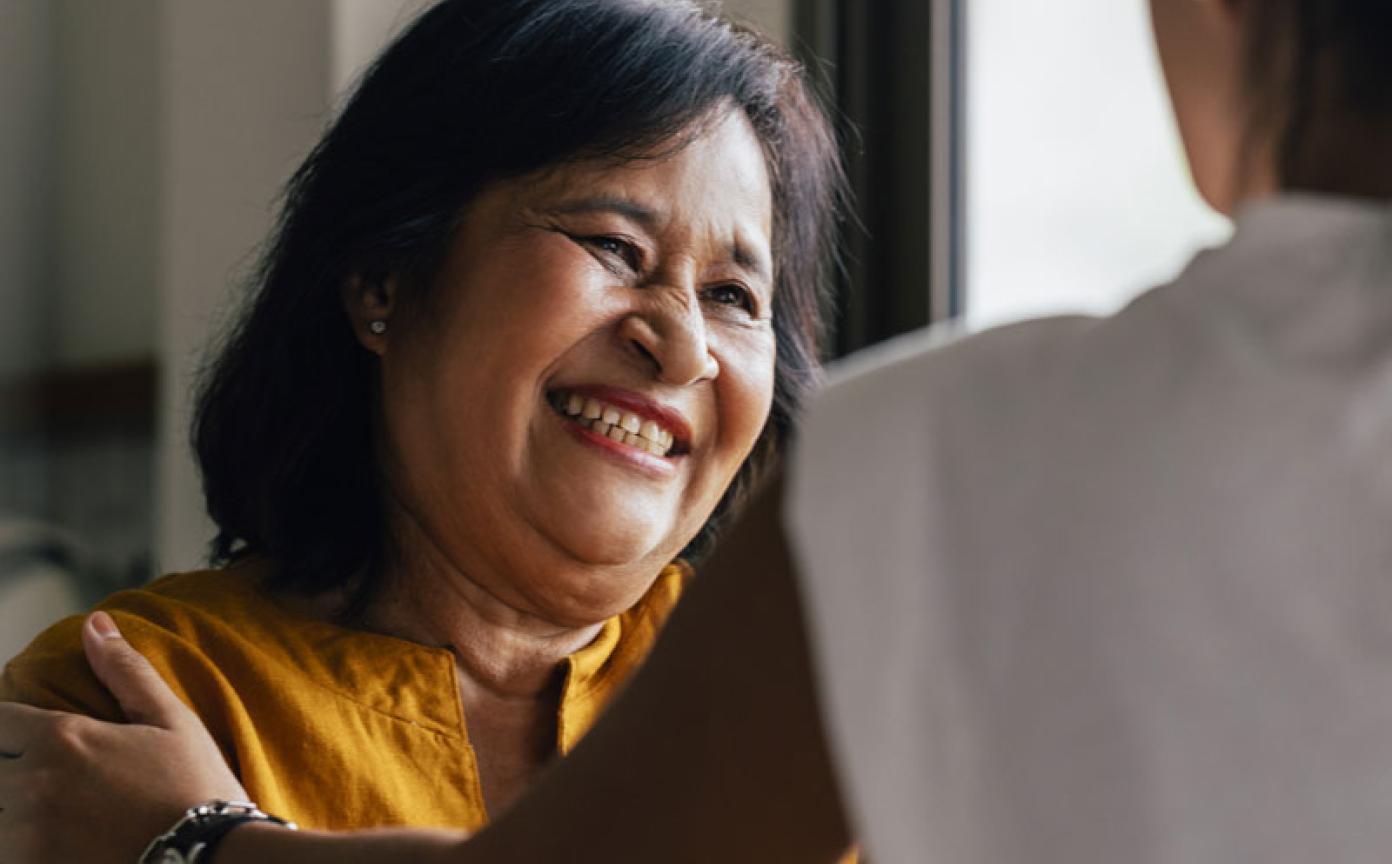 Woman in yellow sit and smiling to a practitioner in appointment