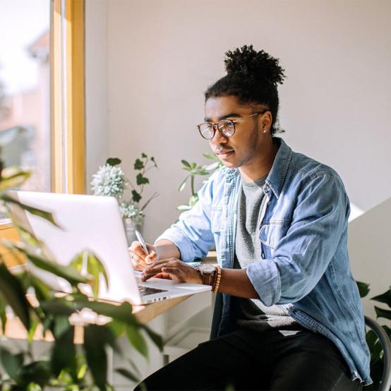 Person working with laptop in a room with plants