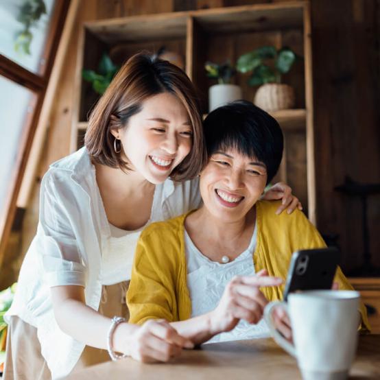 Daughter and mother smiling while watching their cellphone