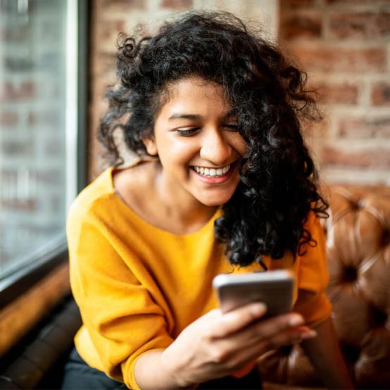 Person smiling with a cellphone in their hands